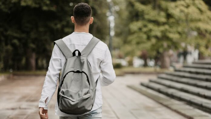 Un joven caminando de espaldas con un bolso