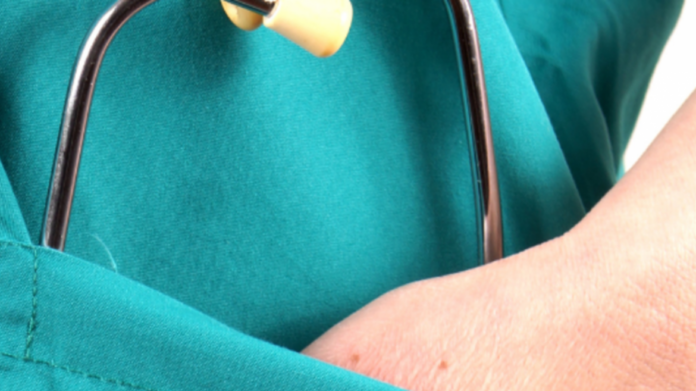 plano del torso de profesional sanitario bata verde mano en uno de los bolsillos