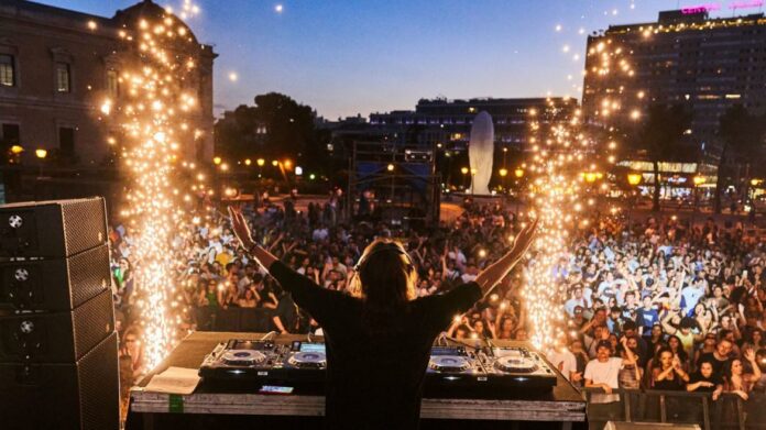 Imagen con DJ frente al público en un concierto y fuegos artificiales